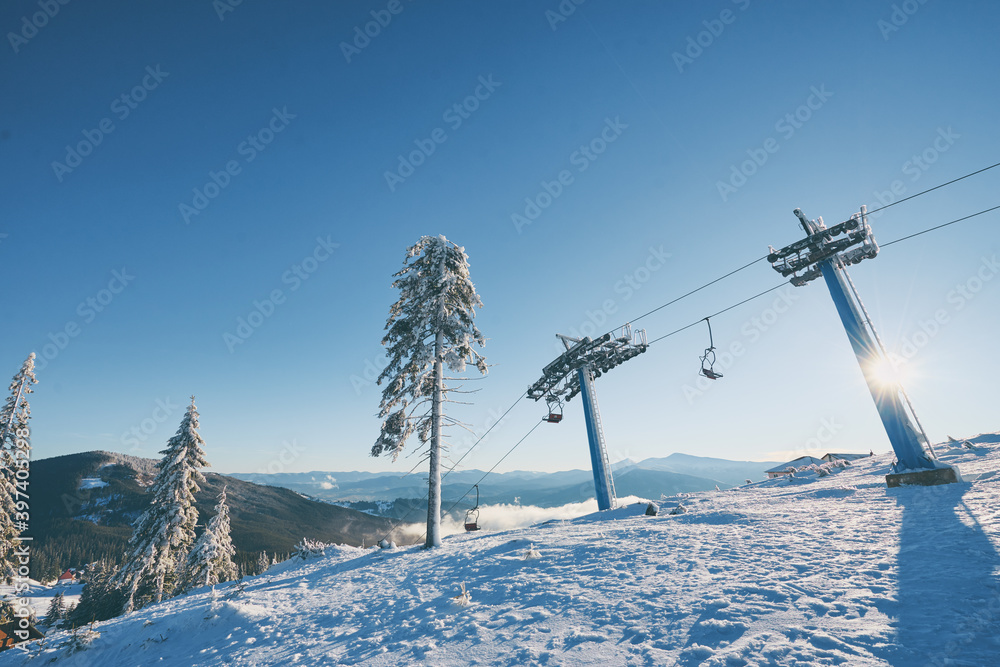 Ski lift with seats going over the mountain and paths from skies and snowboards. Beautiful winter landscape. Ski lift with seats going over the mountain and paths from skies and snowboards. Beautiful winter landscape.