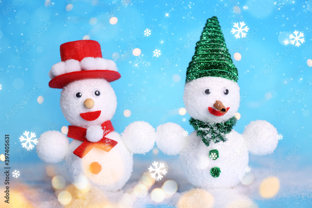 Cute decorative snowmen on light blue background with snowflakes, bokeh effect