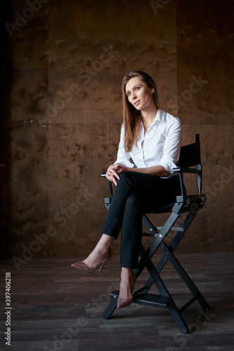 An actress. Portrait of young beautiful emotional sensual woman in white shirt sitting on chair.