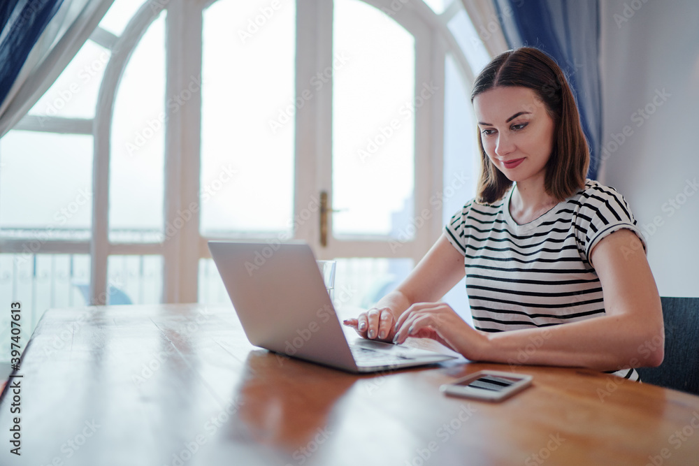 Working at home. Freelance concept. Pretty young woman using laptop at her apartment. Working at home. Freelance concept. Pretty young woman using laptop at her apartment.