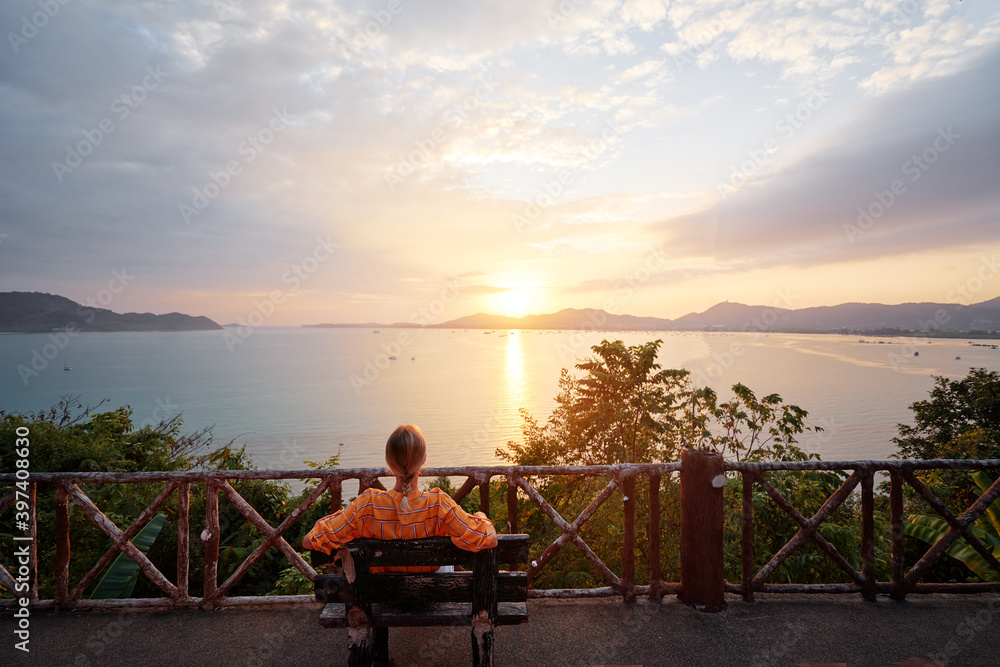 Traveling by Thailand. Young woman enjoying wonderful sunset on Phuket island view point.
