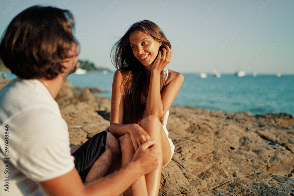 Love and romance. Honeymoon on the sea shore. Beautiful loving couple in white cloth sitting on the beach. Love and romance. Honeymoon on the sea shore. Beautiful loving couple in white cloth sitting on the beach.