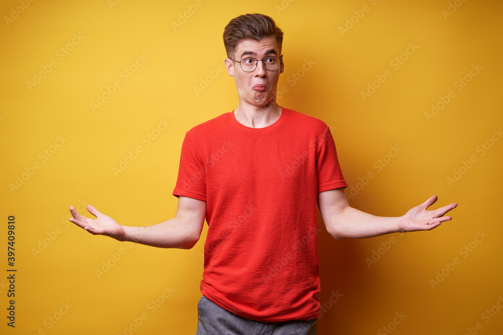 Don't know! Confused young man against yellow background. Don't know! Confused young man against yellow background.