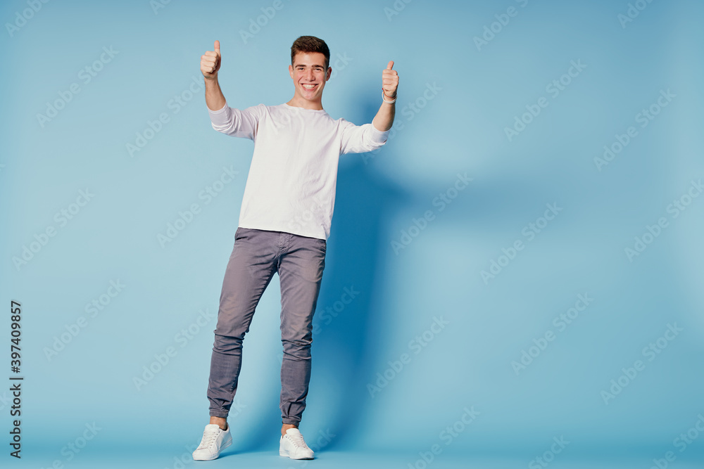 Success! Great job! Happy young man showing thumb up while standing against blue background. Success! Great job! Happy young man showing thumb up while standing against blue background.