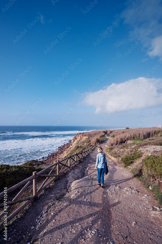 Fototapeta premium Tourism concept. Young traveling woman enjoying ocean view.