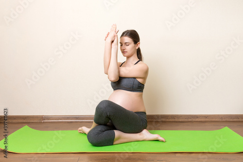 Beautiful pregnant woman doing yoga at home. Pregnancy Yoga and Fitness concept at coronavirus time