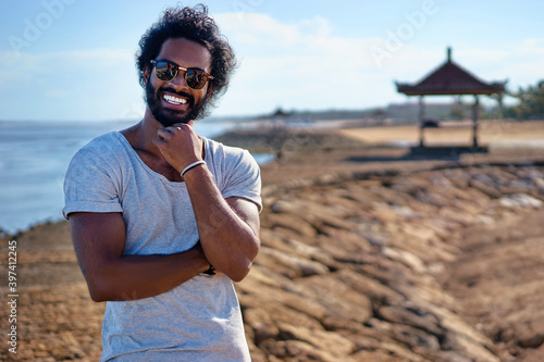 Handsome and confident. Outdoor portrait of smiling young african man on tha beach. © luengo_ua