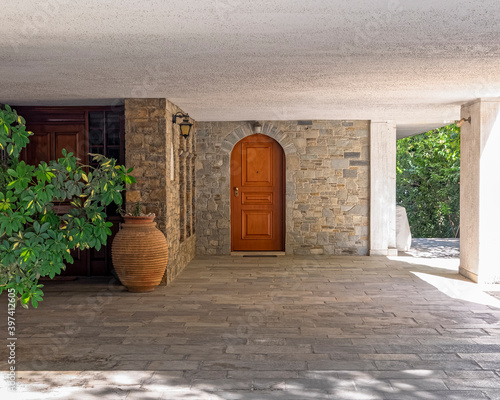 contemporary house entrance with natural wood door, stone covered wall and huge jar, Athens Greece