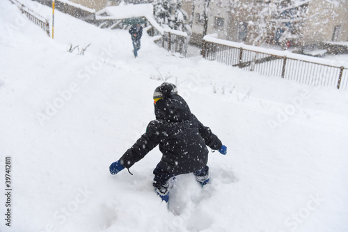 bambino che gioca nella neve nevicata montagna alta montagna grossa nevicata inverno divertimento  photo