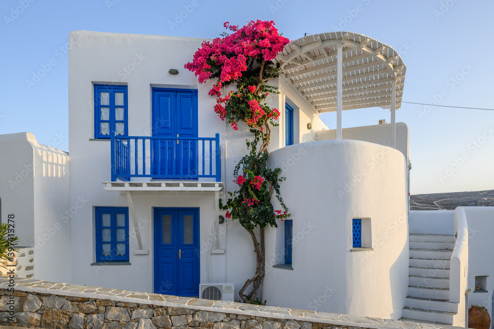Typical Cycladic architecture, Greek whitewashed house with blue windows and summer flowers in Folegandros Island. Greece