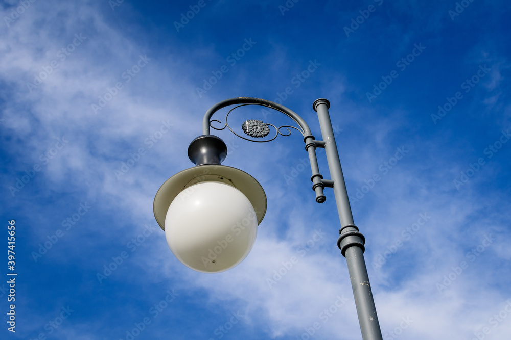 Modern lighting pole with cloudy blue sky in the background in a street in the old city center of Bucharest, Romania. Modern lighting pole with cloudy blue sky in the background in a street in the old city center of Bucharest, Romania.