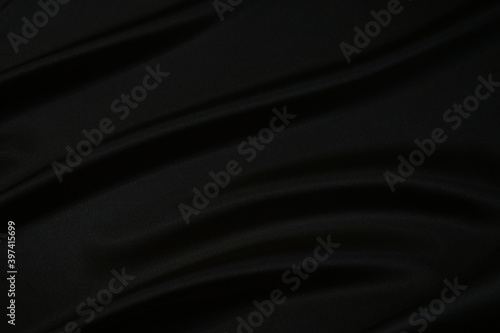 Black silk satin fabric background. Black elegant background. Shiny fabric with wavy folds.