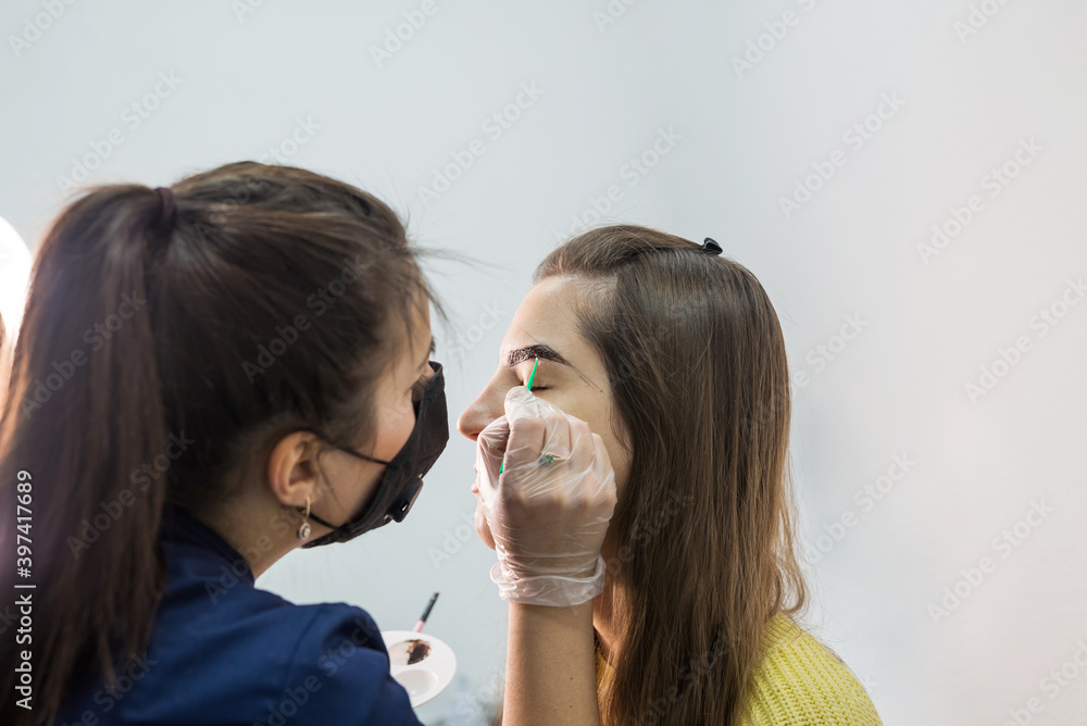 Beautiful young female master makes eyebrow correction procedure. Beautiful young female master makes eyebrow correction procedure.