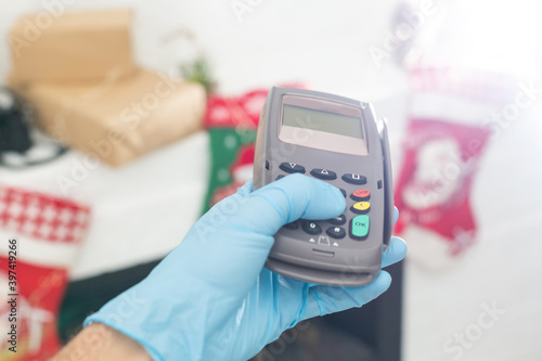 Modern consumer keeping smartphone over cashier-machine to pay for purchase, Christmas decor