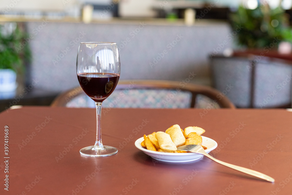 Naklejka premium wineglass, potato wedges, spring rolls on a dark-red table
