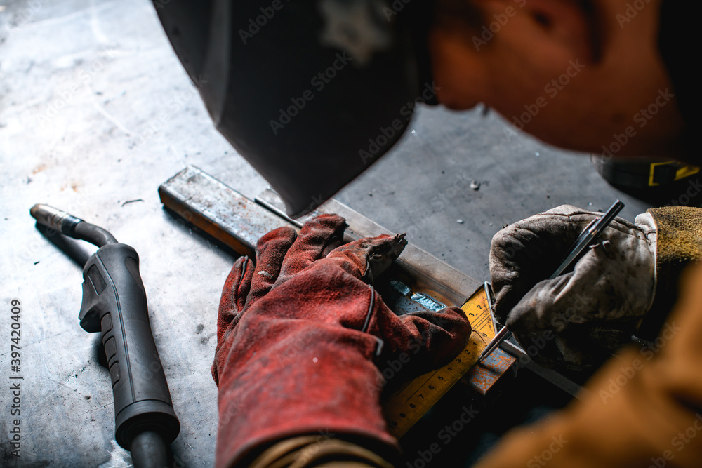 Welder measuring metal profile with square ruler near gun of semi ...
