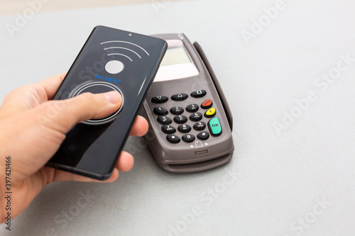 Man using NFC technology on smart phone to pay bill