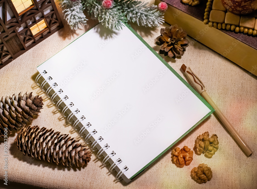 Notepad and pen lie among pine cones, walnuts and Christmas decorations, mockup. Notepad and pen lie among pine cones, walnuts and Christmas decorations, mockup.