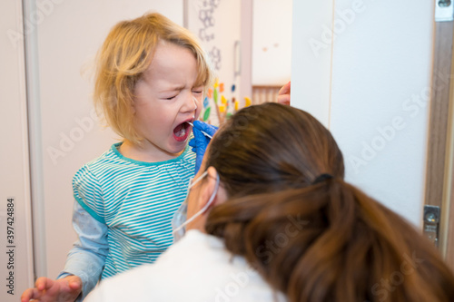 Blonde girl having oropharyngeal swab inserted for covid 19 detection.