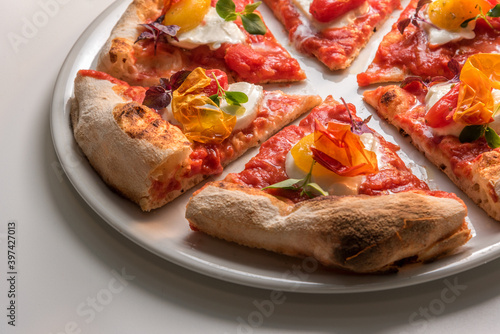 Close up of gourmet pizza slices with tomato, mozzarella, basil and crisp pepper skin. Ready-to-eat pizza
