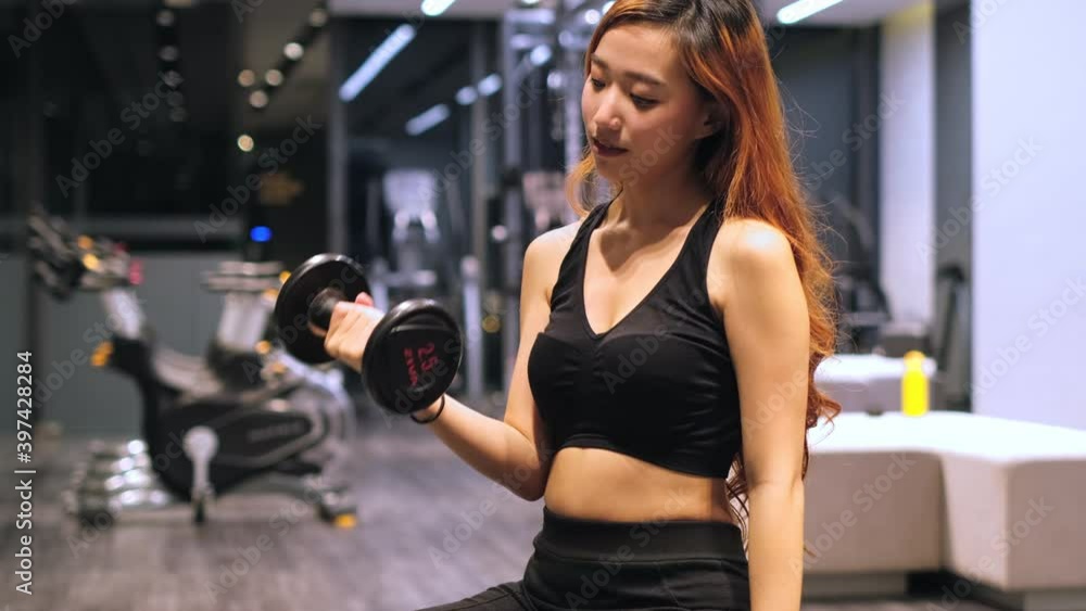 Muscular asian young woman with beautiful body doing exercises . Sporty girl lifting weights in gym. Muscular asian young woman with beautiful body doing exercises . Sporty girl lifting weights in gym.