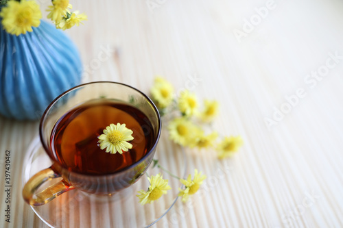 Small Chrysanthemum flower tea cup and flower pot on wooden table  