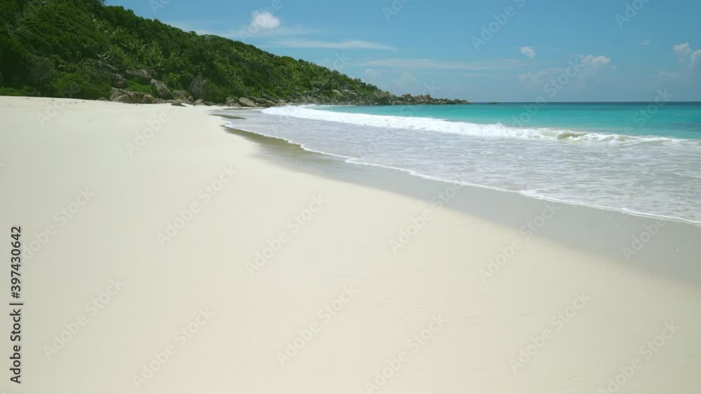 Exotic beach by the ocean with rolling waves on the sandy shore and blue sky Exotic beach by the ocean with rolling waves on the sandy shore and blue sky