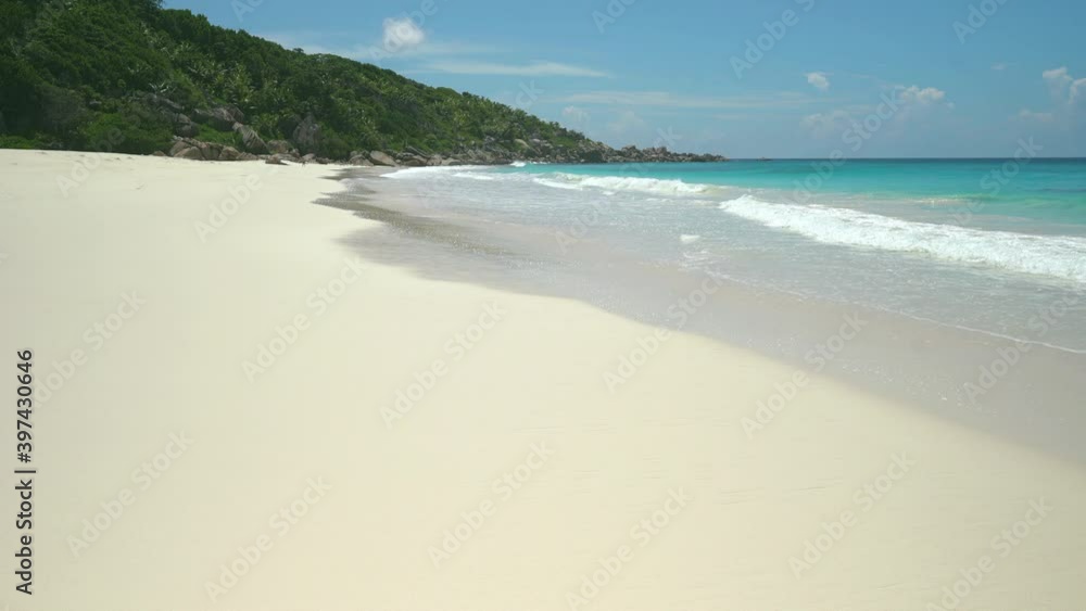 Exotic beach by the ocean with rolling waves on the sandy shore and blue sky Exotic beach by the ocean with rolling waves on the sandy shore and blue sky