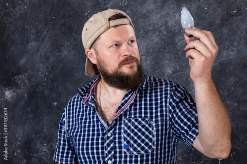 Solid bearded man at casual clothes with a bulb lamp