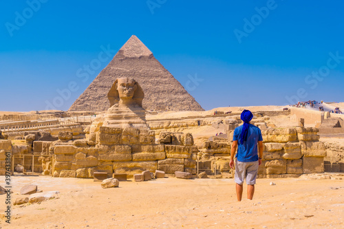 Tela A young man walking towards the Great Sphinx of Giza and in the background the pyramid of Khafre, the pyramids of Giza