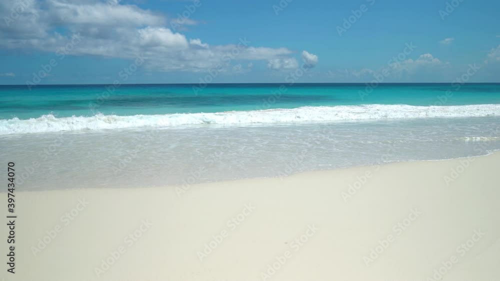 Exotic beach by the ocean with rolling waves on the sandy shore and blue sky Exotic beach by the ocean with rolling waves on the sandy shore and blue sky