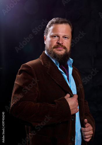 Stylish bearded man dressed in suit studio portrait on black background.