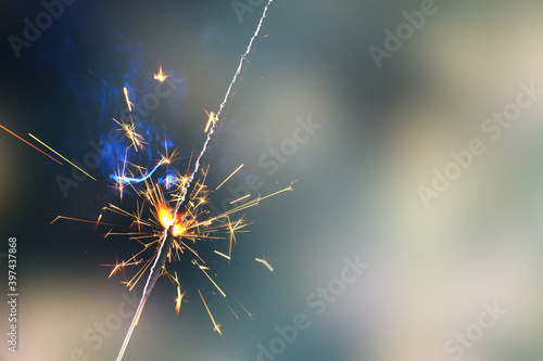 Happy New Year Burning sparkler in female hand on background of christmas tree with lights