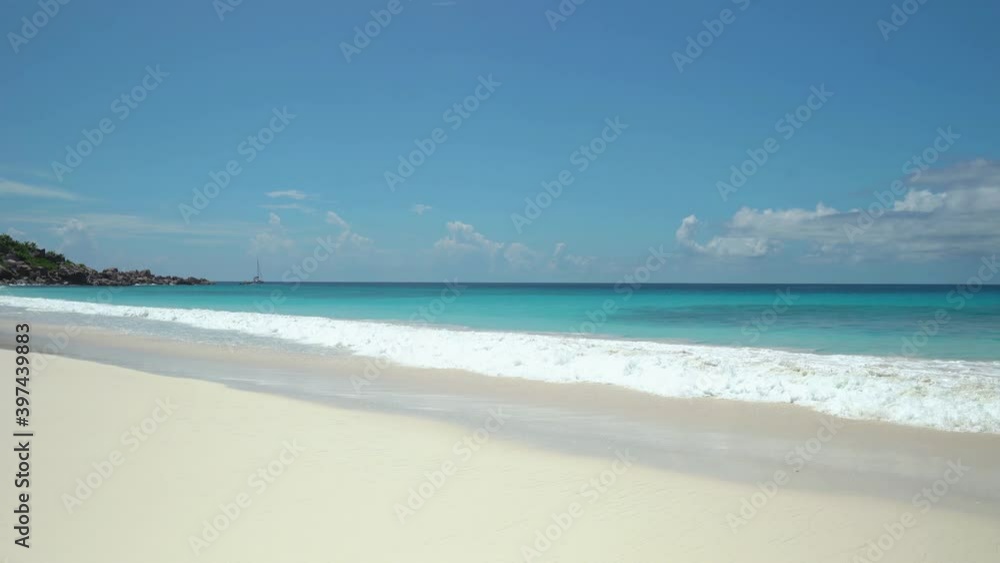 Exotic beach by the ocean with rolling waves on the sandy shore and blue sky Exotic beach by the ocean with rolling waves on the sandy shore and blue sky