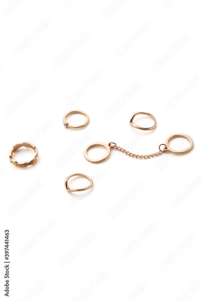 Subject shot of golden rings isolated on white background. Elegant jewelry set consists of six rings: two rings are connected with chain, one ring is decorated with clear crystal. Subject shot of golden rings isolated on white background. Elegant jewelry set consists of six rings: two rings are connected with chain, one ring is decorated with clear crystal.