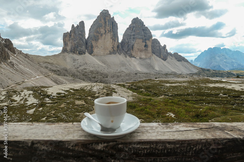 A cup of coffee with the view on the famous Tre Cime di Lavaredo (Drei Zinnen) in Italian Dolomites. The mountains are surrounded by thick clouds. Enjoying the moment. Relaxation and chill.