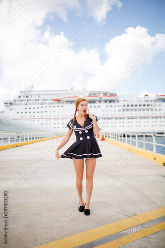 red hair sailor girl in port happy poses with cruise ship  and ocean on background, travel photo content © Bogdan