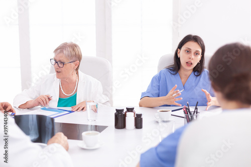 Medical team sitting and discussing about patient diagnosis in conference room. Clinic expert therapist talking with colleagues about disease, medicine professional