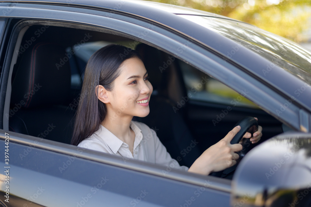 Beautiful young smiling woman driving her car, insurance and finance concept