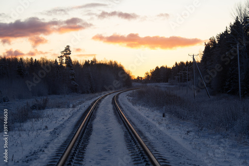 A beautiful winter morning landscape of a railway tracks in the forest. Colorful sunrise scenery of Northern Europe. © dachux21