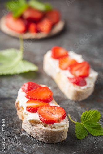 Strawberries sandwiches with cream cheese and on paper, gray background