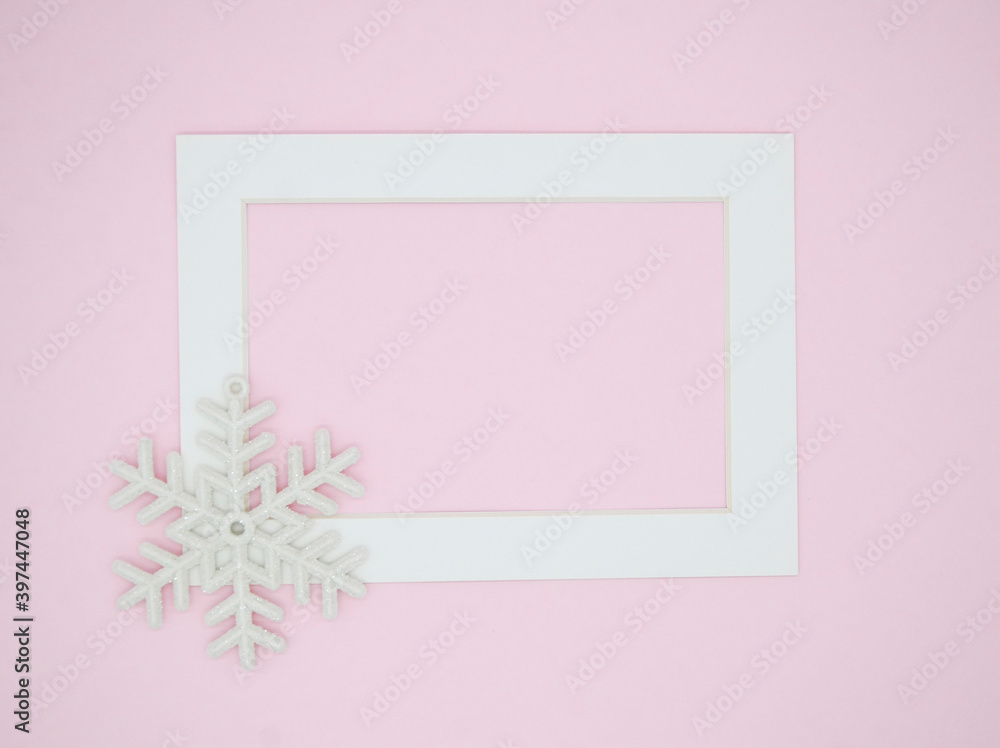 White frame and snowflakes on a pink background. New year's winter card. Christmas flat lay. Minimalism, minimalistic, geometry.