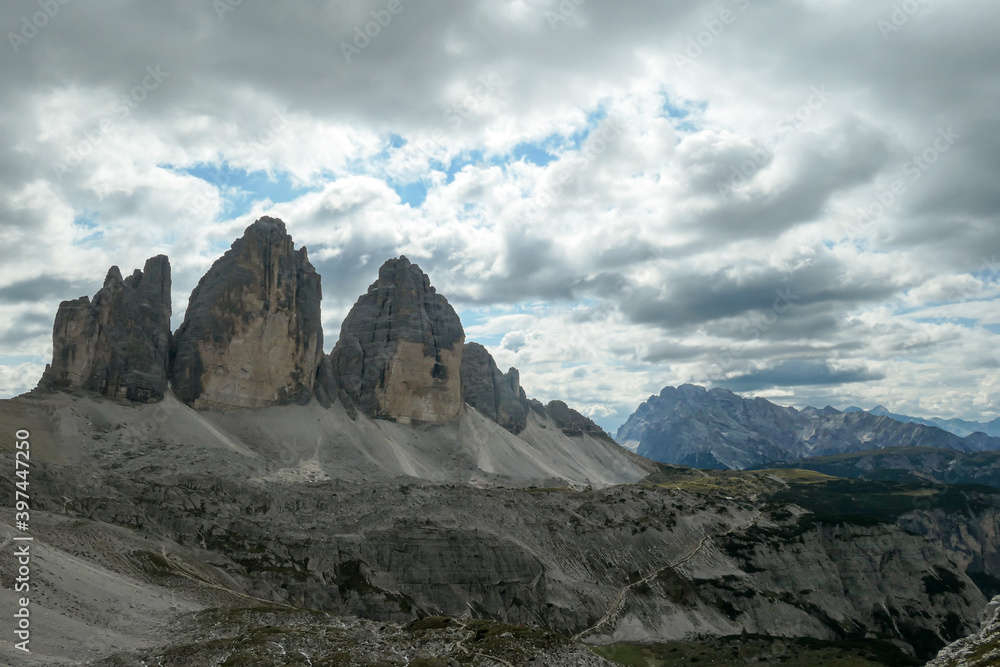 Obraz premium A capture of the famous Tre Cime di Lavaredo (Drei Zinnen) in Italian Dolomites. The mountains are surrounded by thick clouds. There is a lot of landslides and lose stones around. Natural wonder.