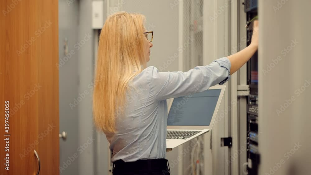 Woman It Engineer Working In Server Room.Network Engineer Work In Data Center.IT Technician Work With Rack Server Cabinet.Digital Secure Specialist In Data Center.It Administrator On Network Hardware Woman It Engineer Working In Server Room.Network Engineer Work In Data Center.IT Technician Work With Rack Server Cabinet.Digital Secure Specialist In Data Center.It Administrator On Network Hardware
