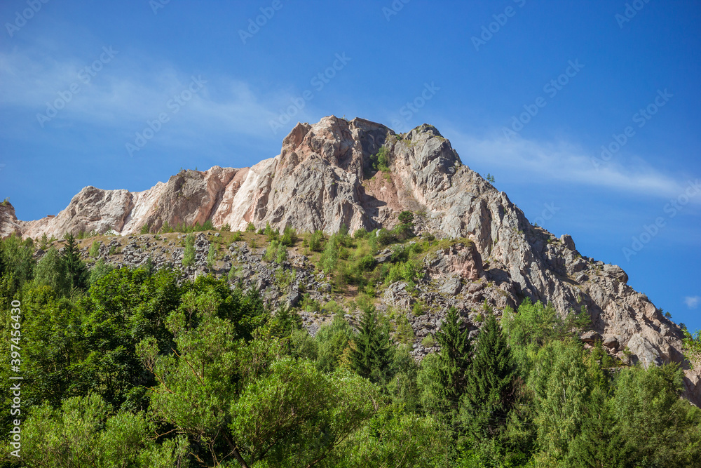 View of the mountain peak below the forest. Romanian mountain near Bicaz Gorge. Carpathian mountains rare massive and pine forest landscape Romanian countryside in summer sunny day