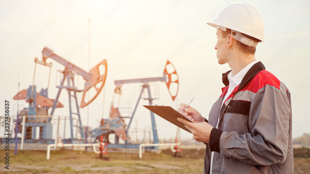 engineer writing on clipboard in oil field. Industrial, oil and gas concept. engineer writing on clipboard in oil field. Industrial, oil and gas concept.
