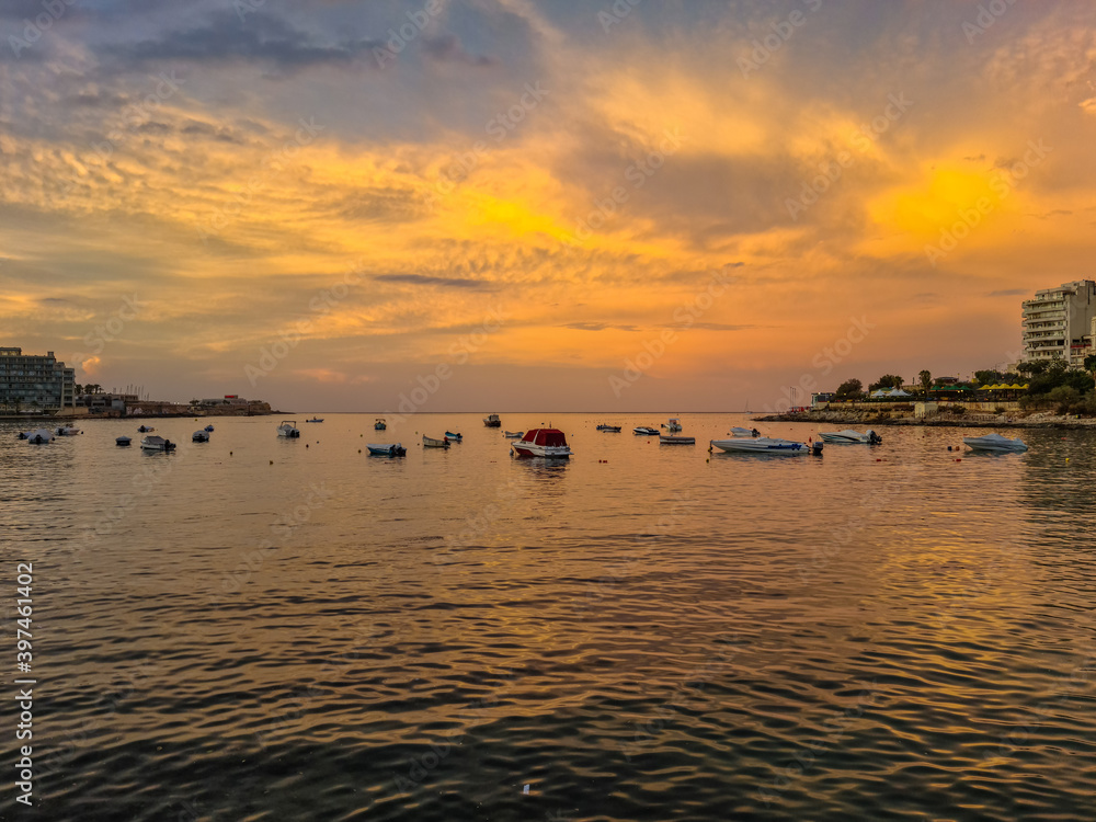 Golden coloured clouds during sunset over the yachts in Saint Julian’s Bay, between Saint Julian’s and Sliema, Malta.