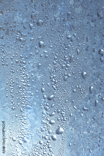 The texture of frozen drops of condensation on a transparent glass window. Water drops. Rain. Abstract texture background. A sharp cold snap, a frozen drop of water on the glass in winter © Aleksandr