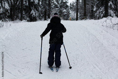 little girl skiing in the winter forest