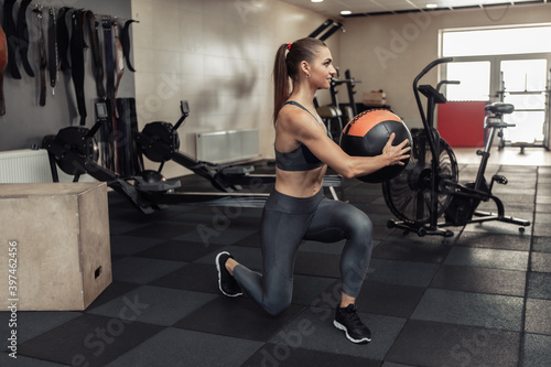 Young cross fit woman exercising with medicine ball in the modern gym. Functional training. Healthy lifestyle